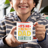 Smiling child holding the It’s Me Hi I’m the Dad mug with a red handle