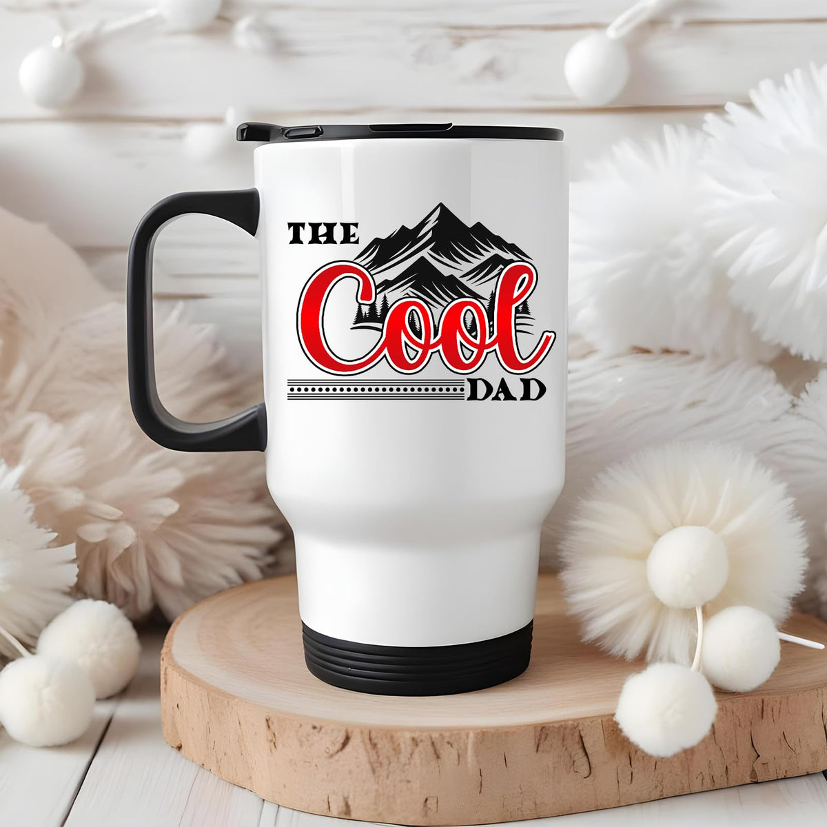 The Cool Dad mountains travel mug on a wooden slice with white pom-poms