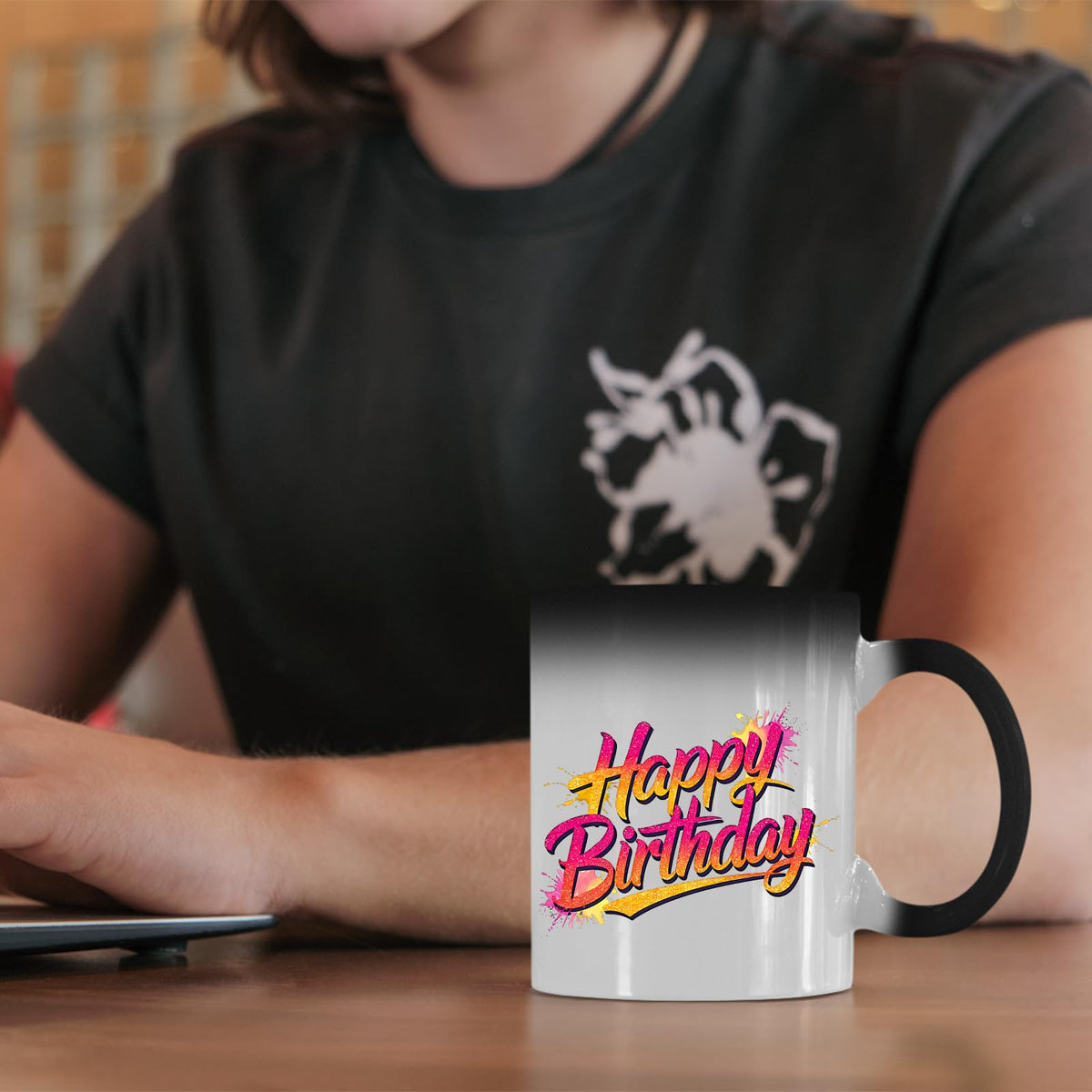 Happy Birthday pink and gold colour changing mug on a desk beside a laptop