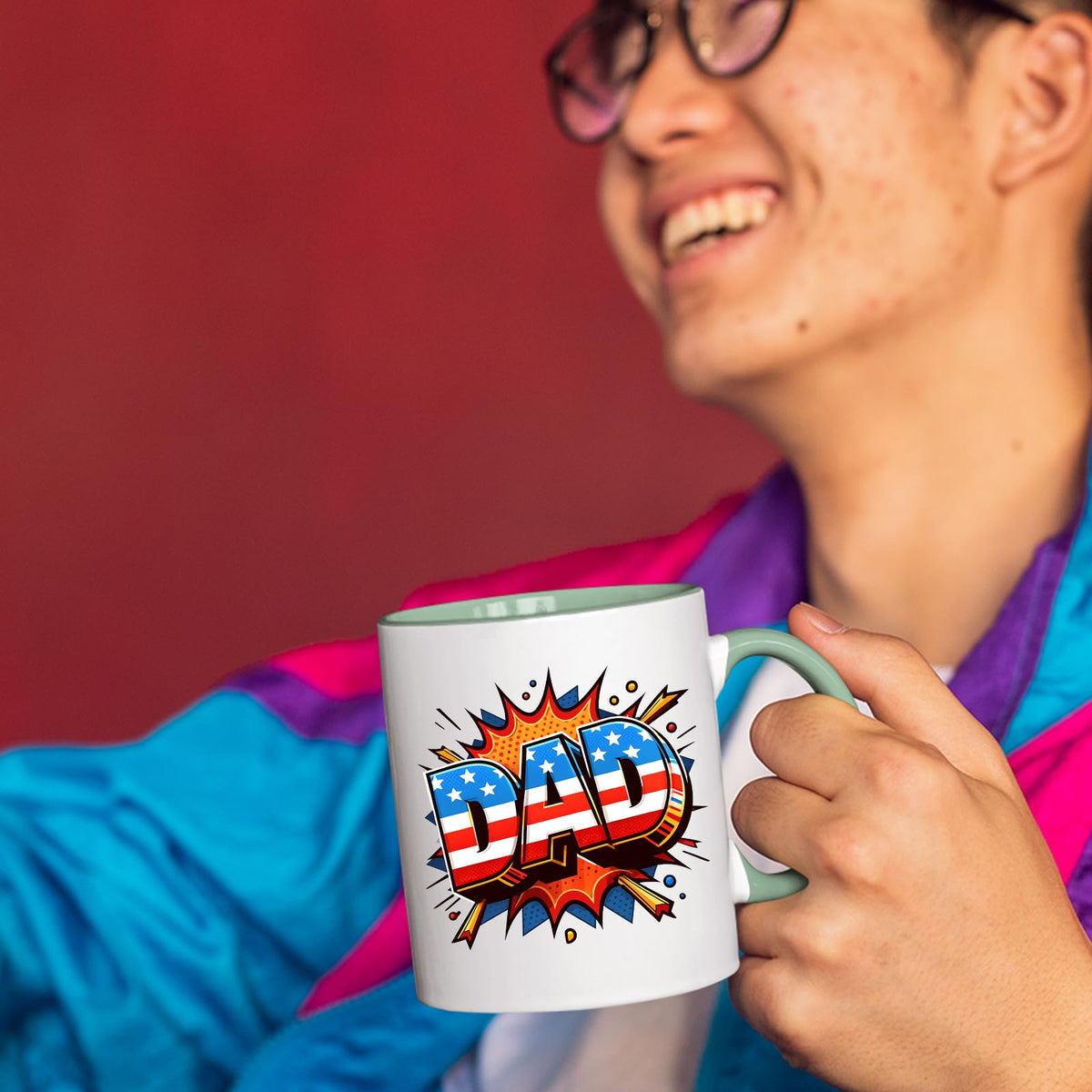 Smiling person in a colourful jacket holding the Stars and Stripes DAD mug with a light green handle