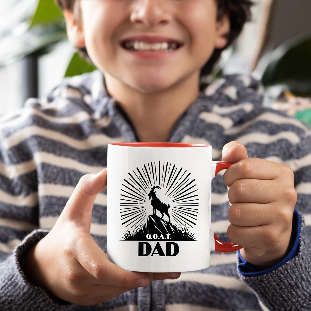 Smiling child holding the GOAT Dad mug with a red handle