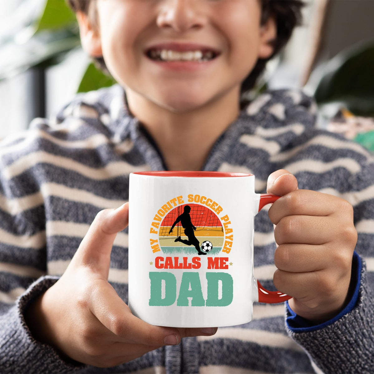 Smiling child holding the Soccer Dad mug with a red handle