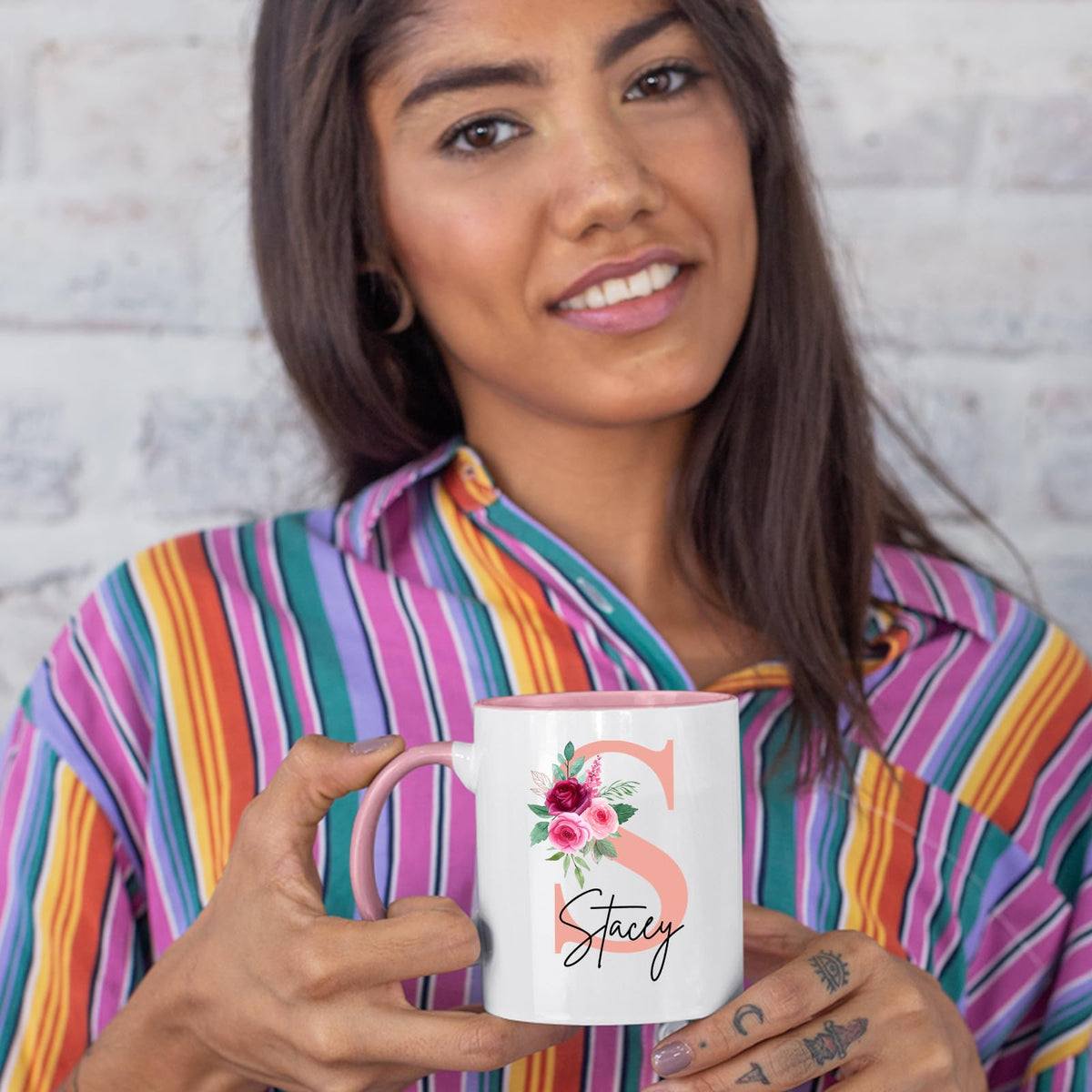 Woman in a striped shirt holding a colour handle mug with a blush pink initial with roses and an example name