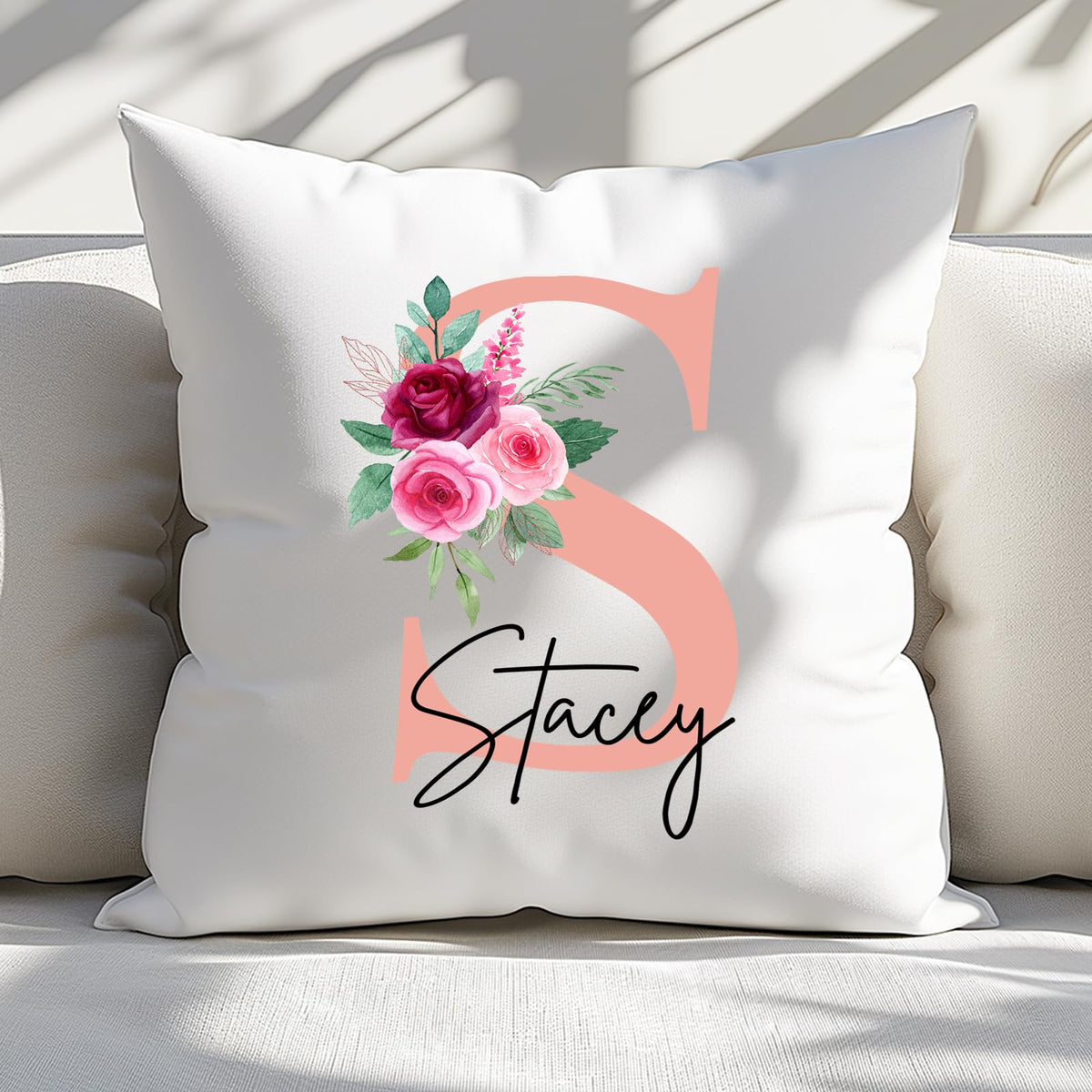 Cushion with a blush pink initial with roses and an example name on a sofa