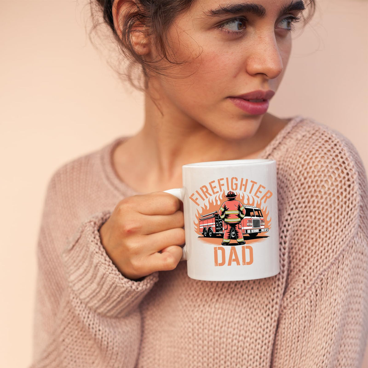 Woman in a pink jumper holding the Firefighter Dad mug