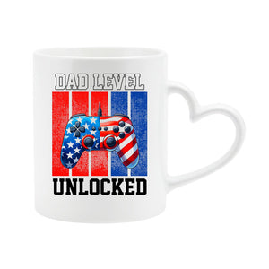 White heart-handle mug with a stars-and-stripes game controller and “Dad level unlocked”