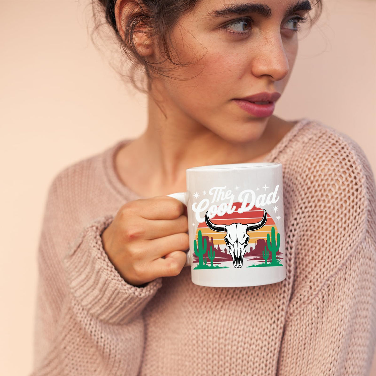Woman in a pink jumper holding the The Cool Dad bull skull mug