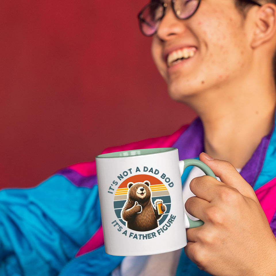 Smiling person in a colourful jacket holding the Dad Bod bear mug with a light green handle