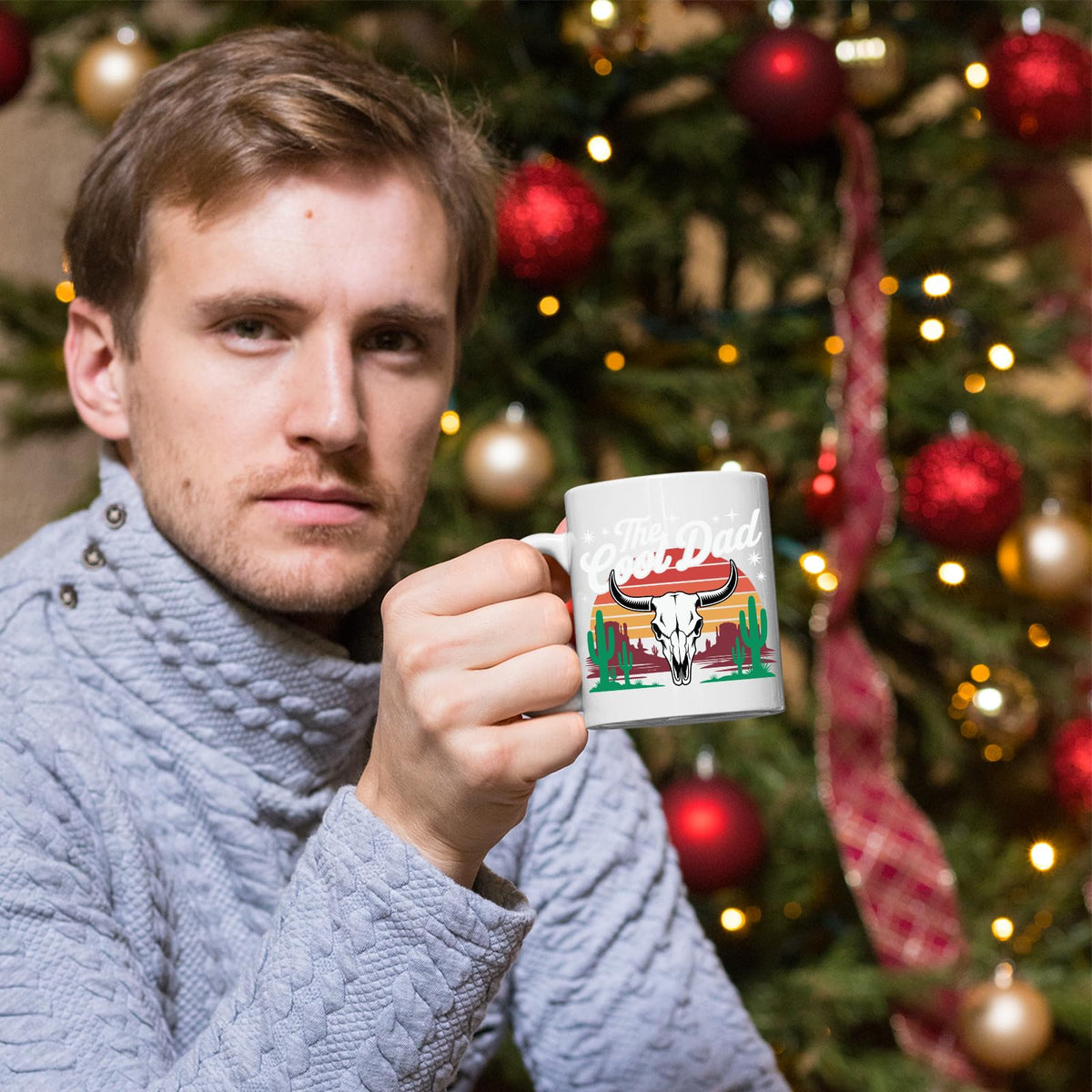 Man holding the The Cool Dad bull skull mug in front of a Christmas tree
