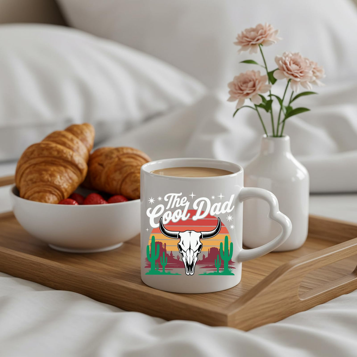 The Cool Dad bull skull heart-handle mug on a breakfast tray with croissants and flowers