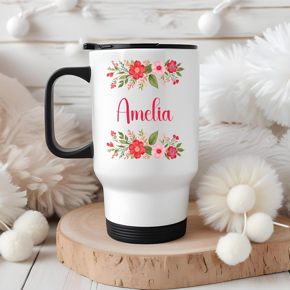 Travel mug with a red flower border around an example name on a wooden board with white pompoms