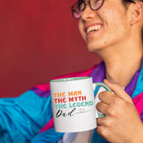 Smiling person in a colourful jacket holding the The Man the Myth Dad mug with a light green handle
