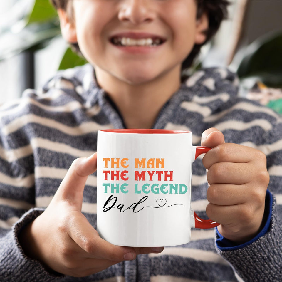 Smiling child holding the The Man the Myth Dad mug with a red handle