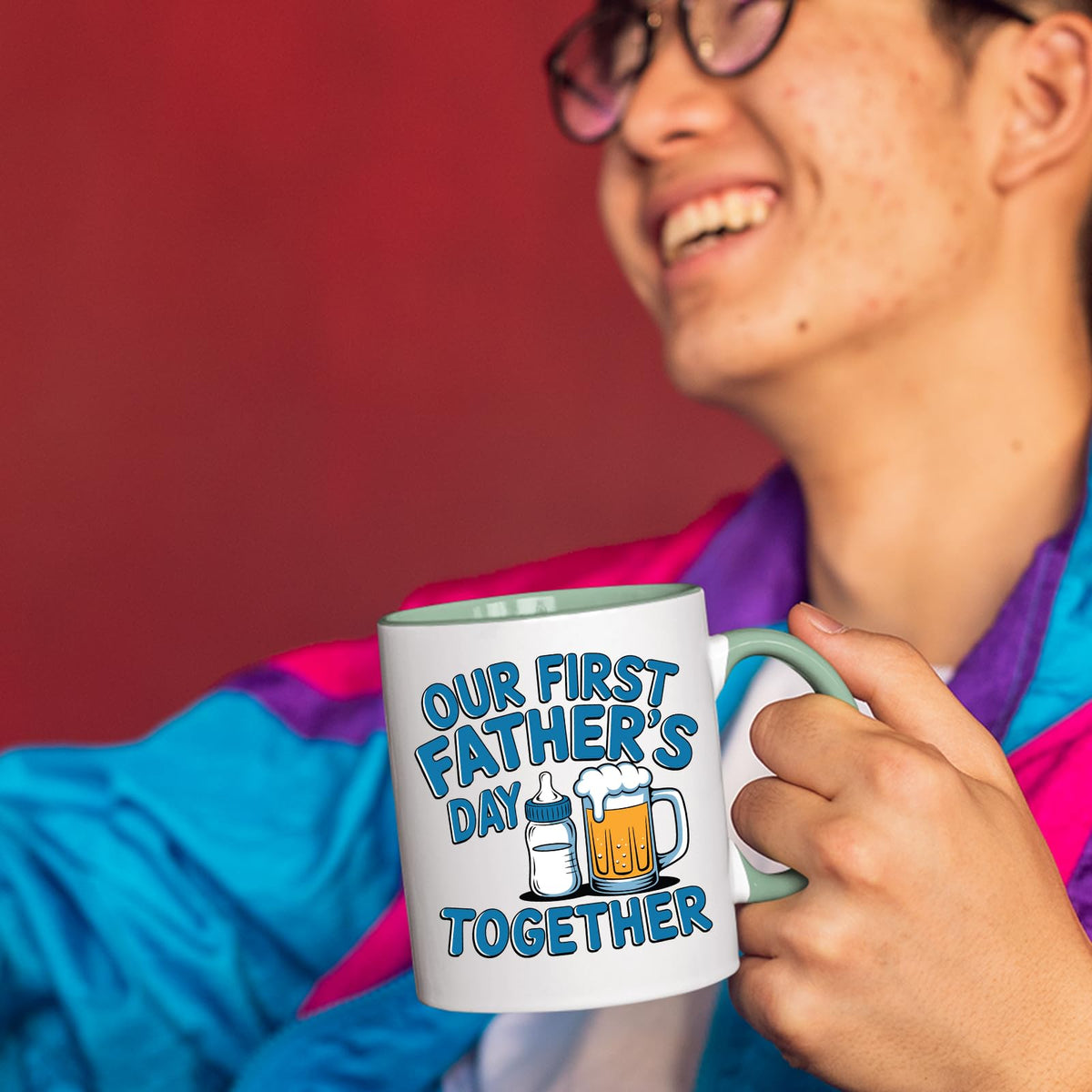 Smiling person in a colourful jacket holding the First Father’s Day bottle and beer mug with a light green handle