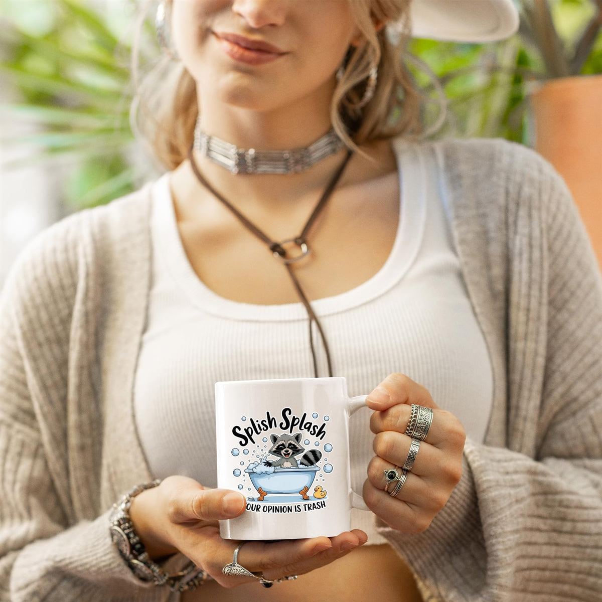 Woman in a cardigan holding the Splish Splash raccoon mug
