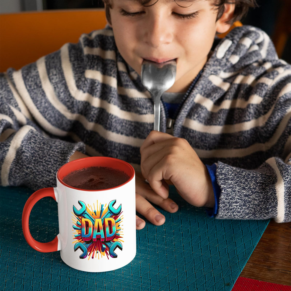 Child with a spoon next to the DAD spanners mug with a red handle