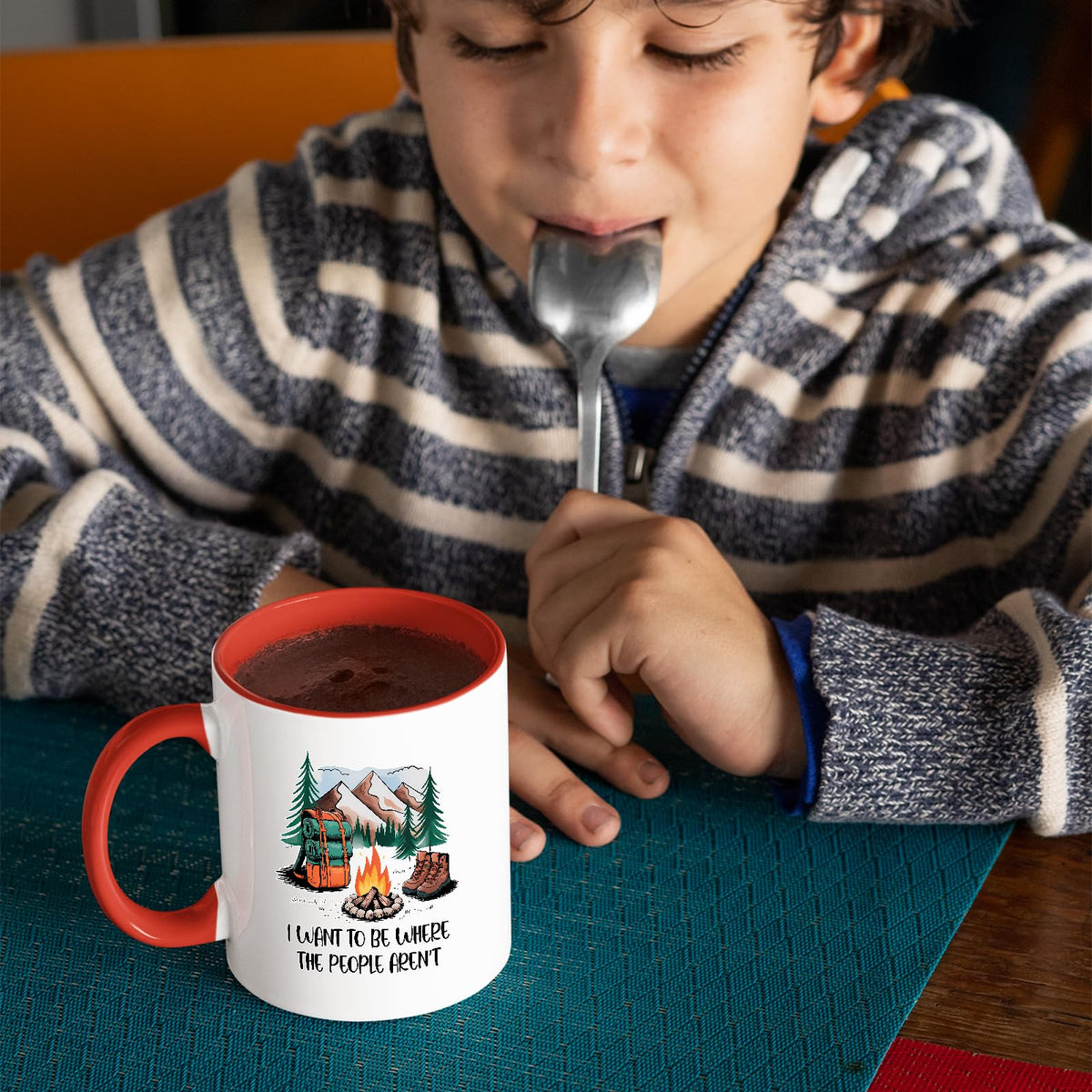 Child with a spoon next to the camping escape mug with a red handle