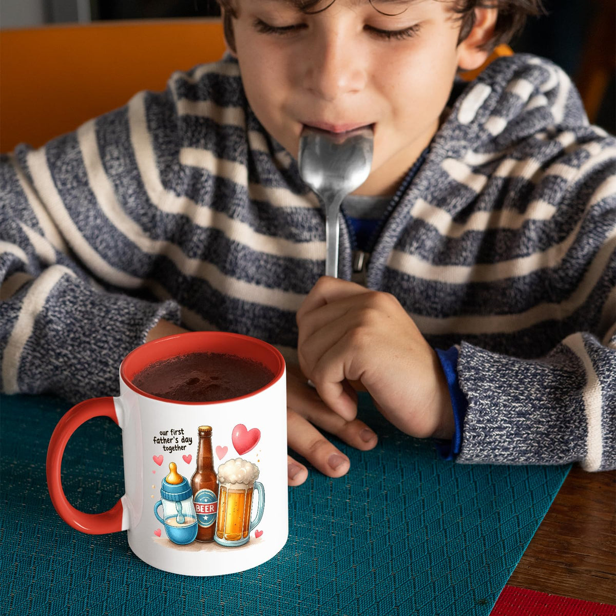 Child with a spoon next to the First Father’s Day hearts mug with a red handle