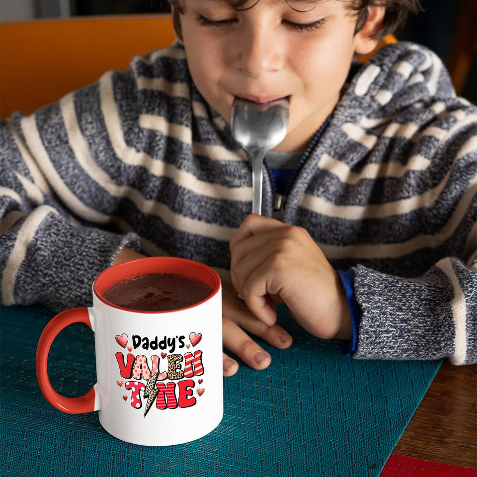 Child with a spoon next to the Daddy’s Valentine mug with a red handle