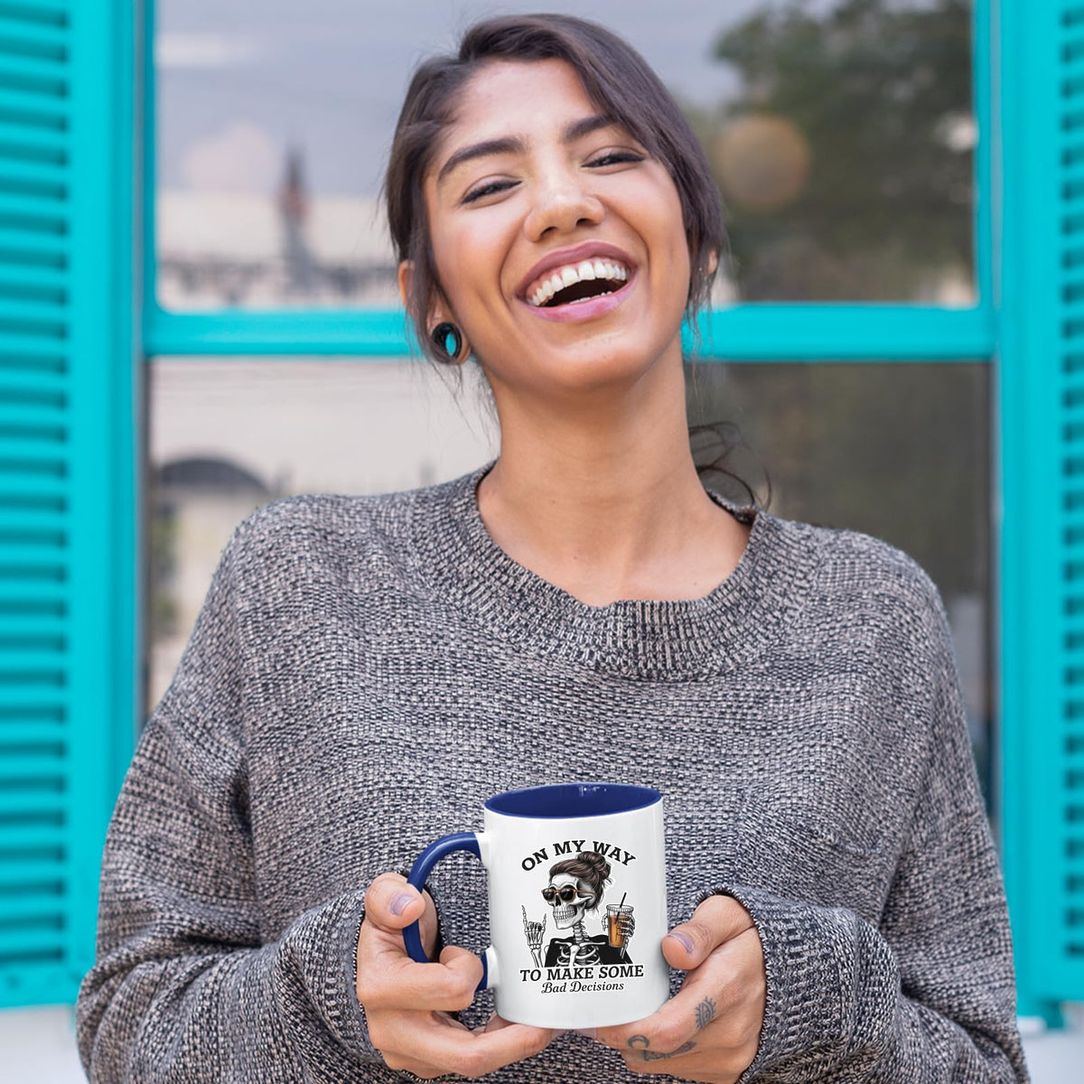 Laughing woman holding the Bad Decisions skeleton mug with a dark blue handle
