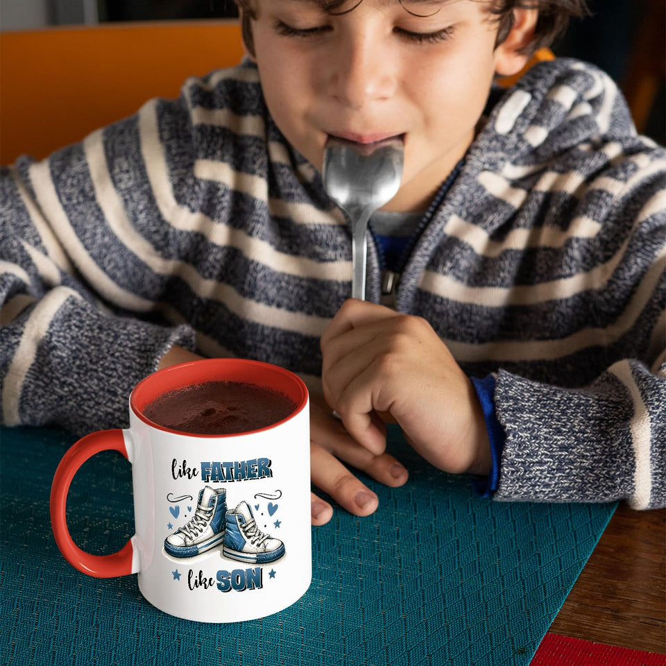 Child with a spoon next to the Like Father Like Son mug with a red handle