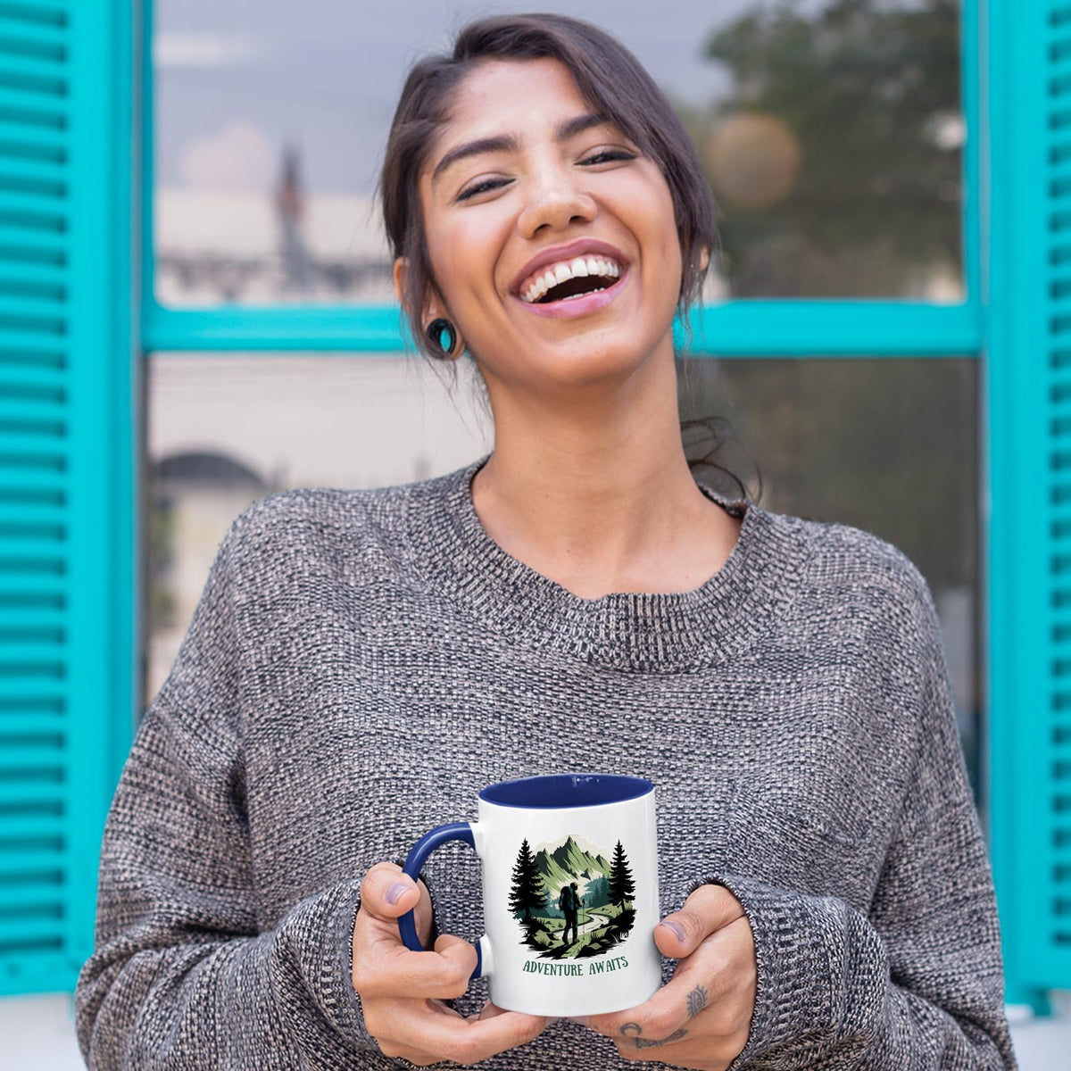 Laughing woman holding the Adventure Awaits hiker mug with a dark blue handle
