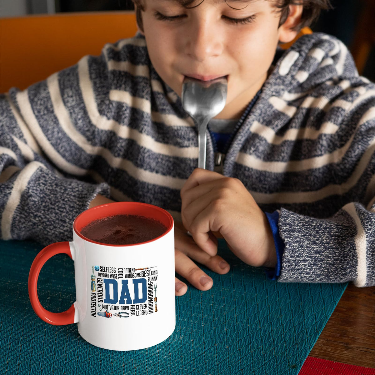 Child with a spoon next to the DAD word cloud mug with a red handle