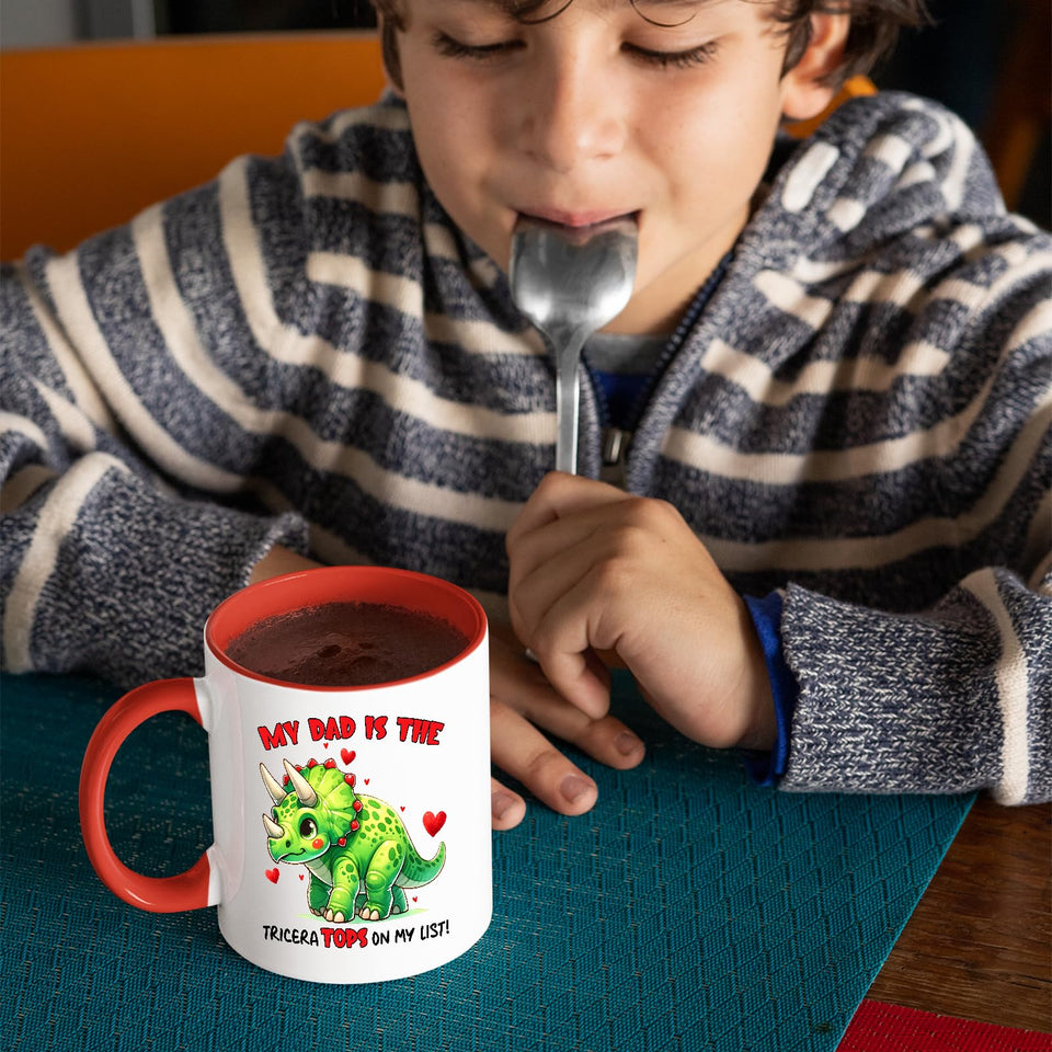Child with a spoon next to the Triceratops dad mug with a red handle