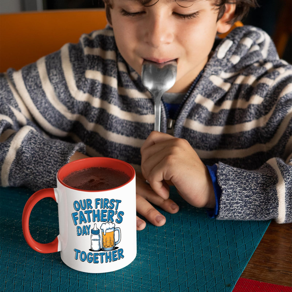 Child with a spoon next to the First Father’s Day bottle and beer mug with a red handle