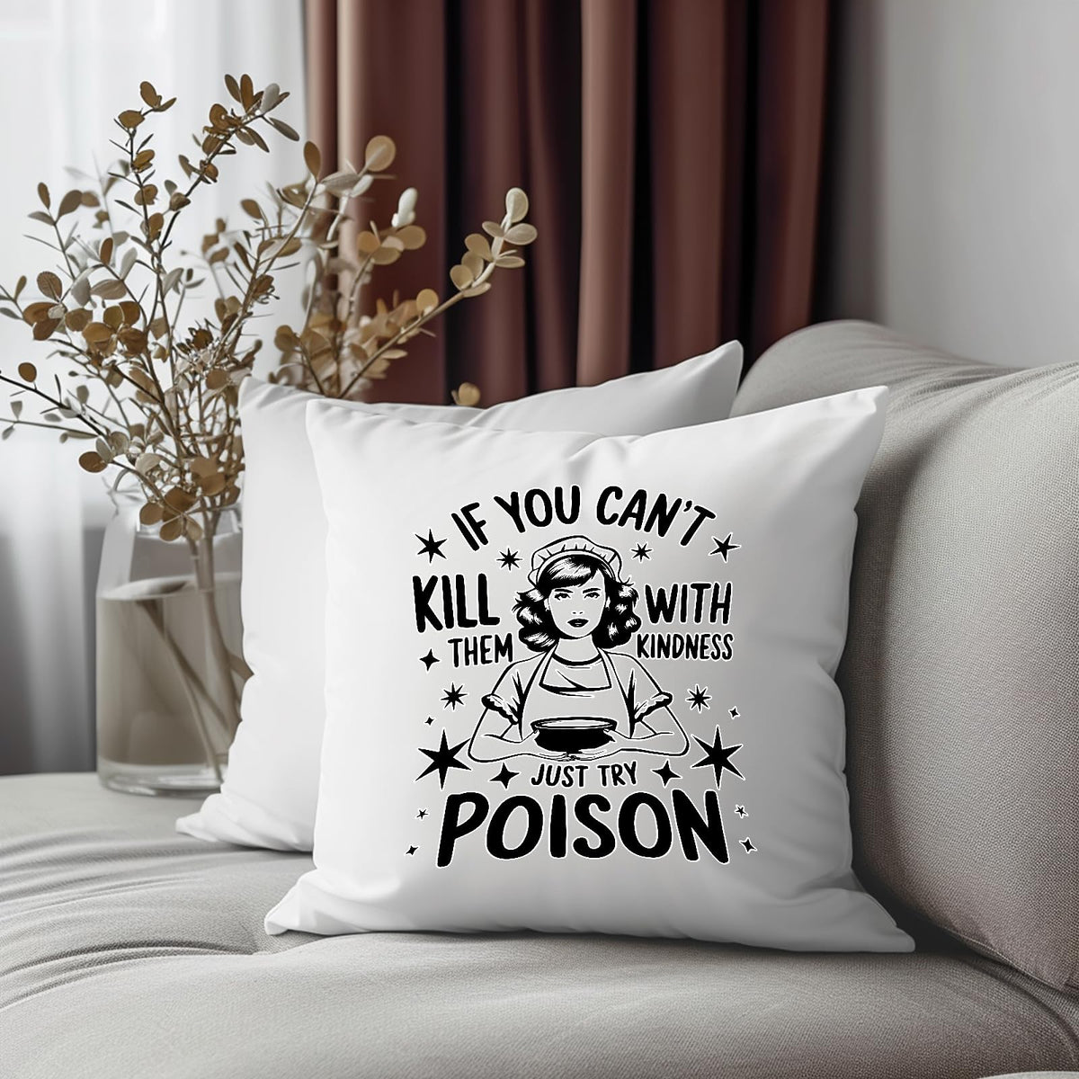 Just Try Poison cushion on a grey sofa beside dried flowers