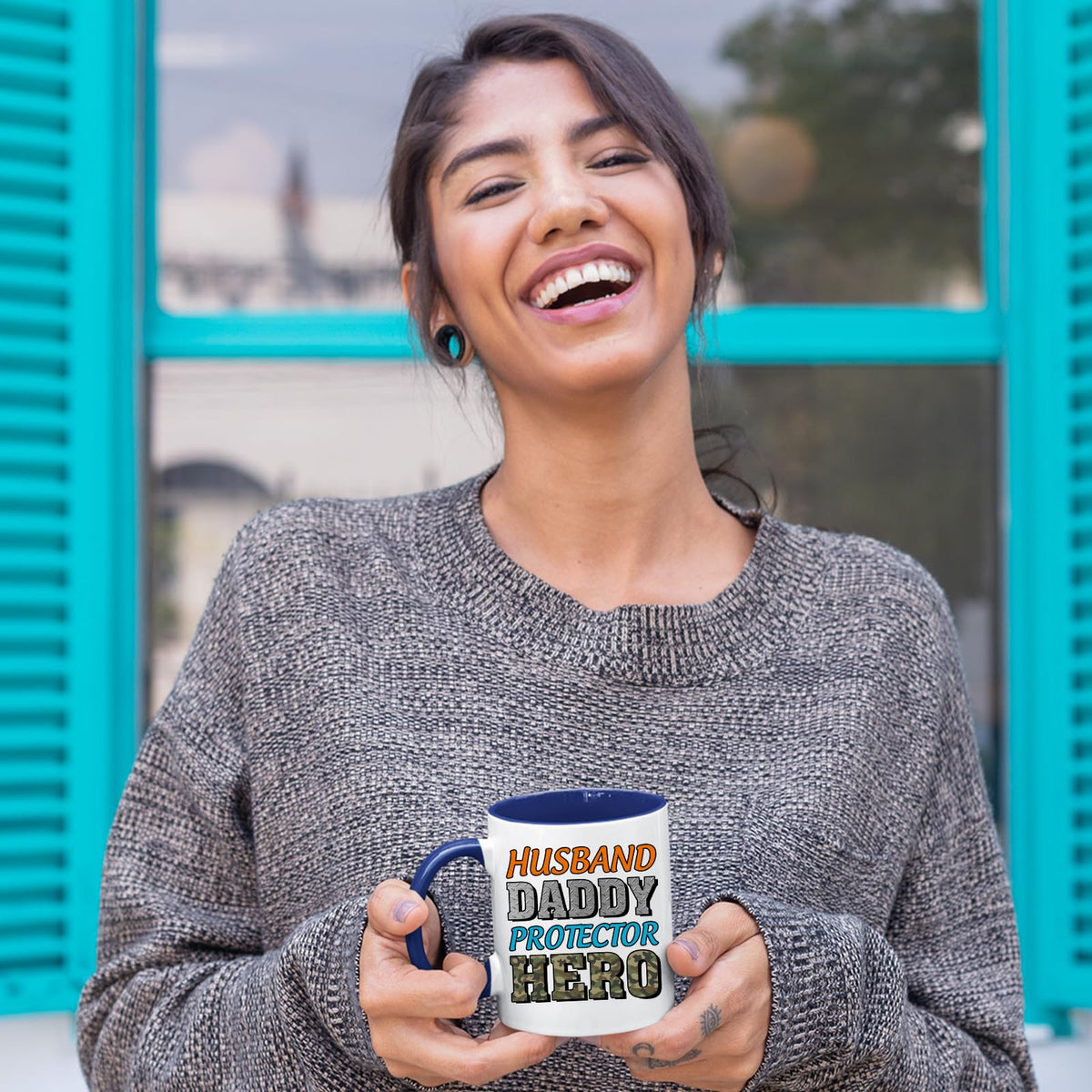 Laughing woman holding the Husband Daddy Protector Hero camo mug with a dark blue handle