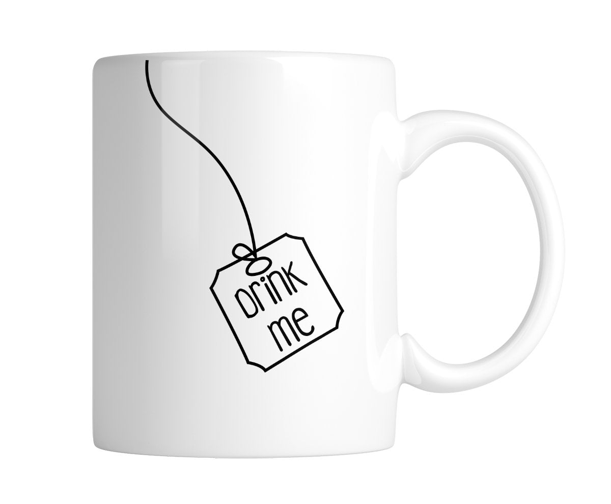 White mug with a hanging tea-bag tag that says “Drink Me” in simple black line art, handle on the right