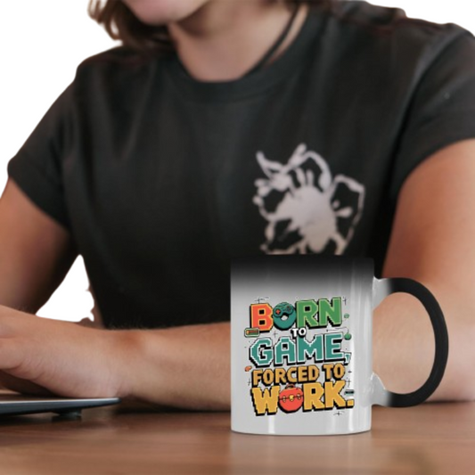 Person holding the colour changing mug with retro “Born to Game, Forced to Work” lettering