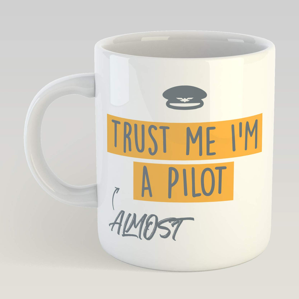 White mug with a pilot's cap and “Trust Me I'm Almost A Pilot” on orange banners