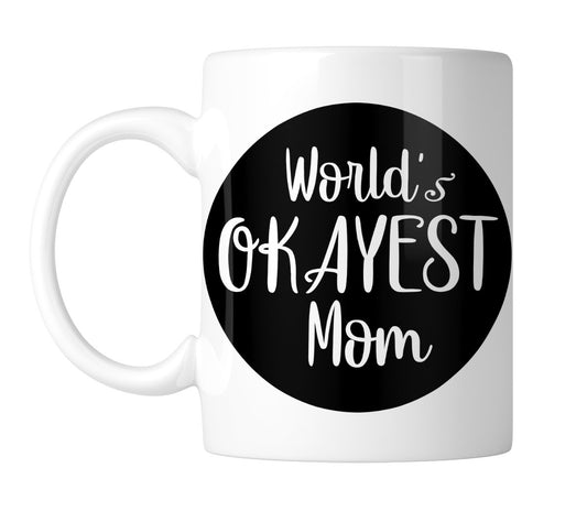 White mug with “World's Okayest Mom” in white on a black circle, handle on the left